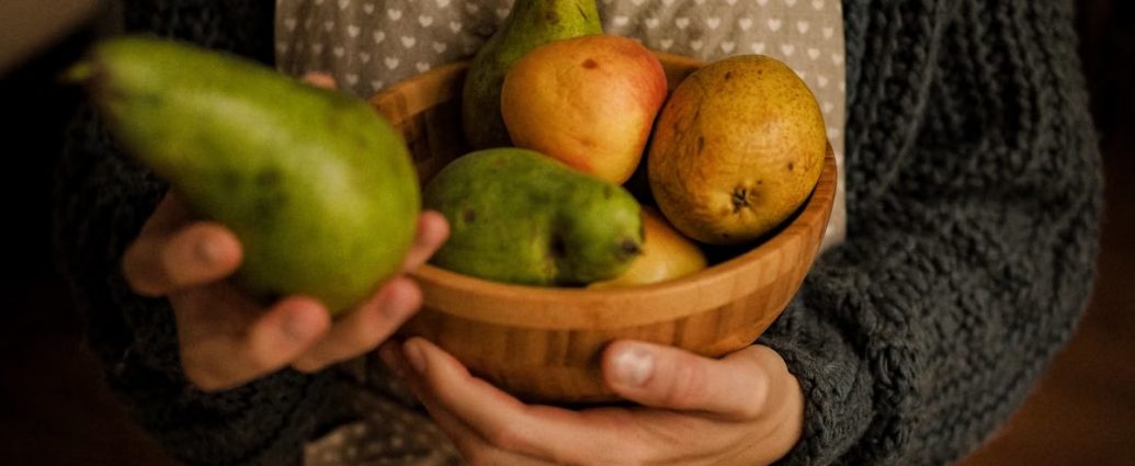 Cozy scene of a person holding a wooden bowl filled with pears and apples.