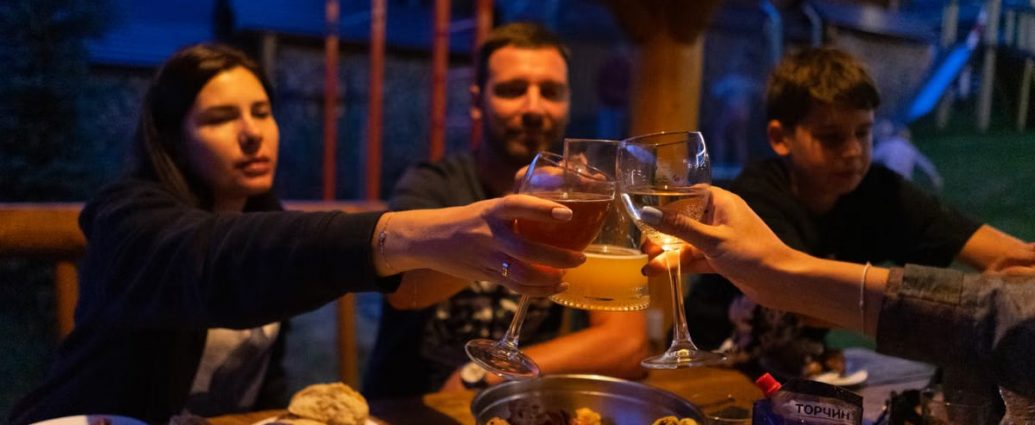 Friends clinking glasses at an outdoor dinner party, enjoying food and drinks.